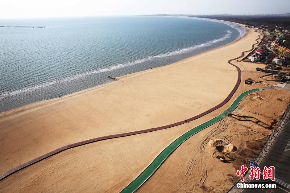 3月13日，秦皇島萬(wàn)米臨海沙灘木棧道。據(jù)了解，該木棧道全長(zhǎng)約4200米，與北戴河區(qū)原有的7500米木棧道對(duì)接后全線總長(zhǎng)度1.17萬(wàn)米，整個(gè)木棧道東起秦皇島體育基地游船碼頭，西至北戴河濕地公園，呈波浪形蜿蜒10.4公里海岸線。 中新社發(fā) 曹建雄 攝 CNSPHOTO